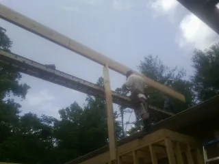 Carpenter setting a ridge beam over a new addition frame — Ice Dam Removal by Roofing Brothers in Pinson