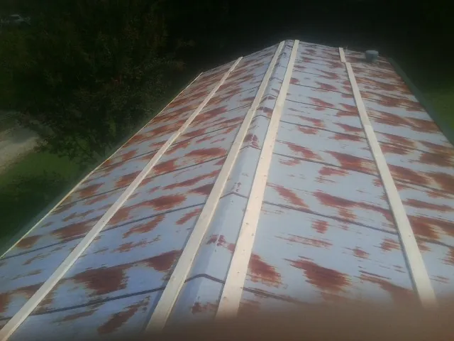Rusted metal roof panels with new wood purlins before replacement — Storm Damage Roof Repair in Pinson by Roofing Brothers