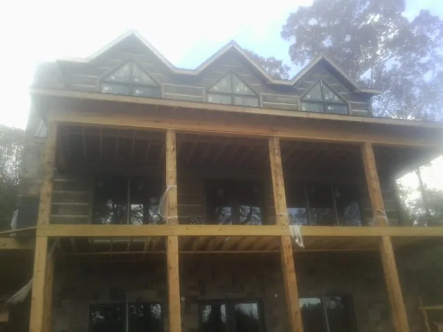 Dormers and porch framing on a large log home under construction — Roof Coating work by our crew in Pinson