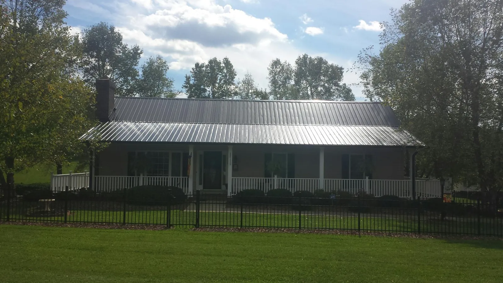Gray metal roof on a brick ranch with a full width front porch — Gutter Guard Installation work by our crew in Pinson